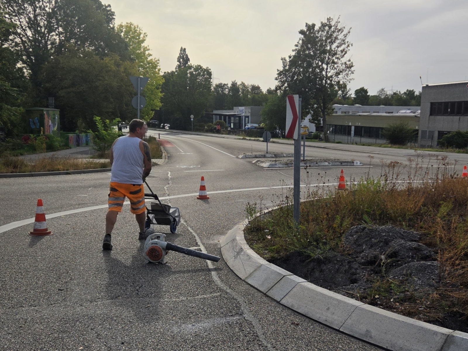 Arbeiter mit Werkzeug an den inneren Bordsteinen des Kreisverkehrs.