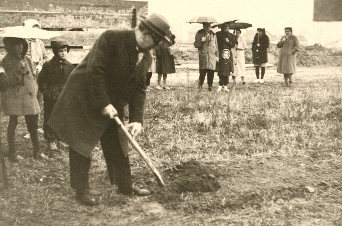 Der Wieslocher Bürgermeister Philipp Hilswicht beim Spatenstich für den Kindergarten in Frauenweiler im Dezember 1961. Die Regenschirme der Zuschauer im Hintergrund lassen das schlechte Wetter erahnen.