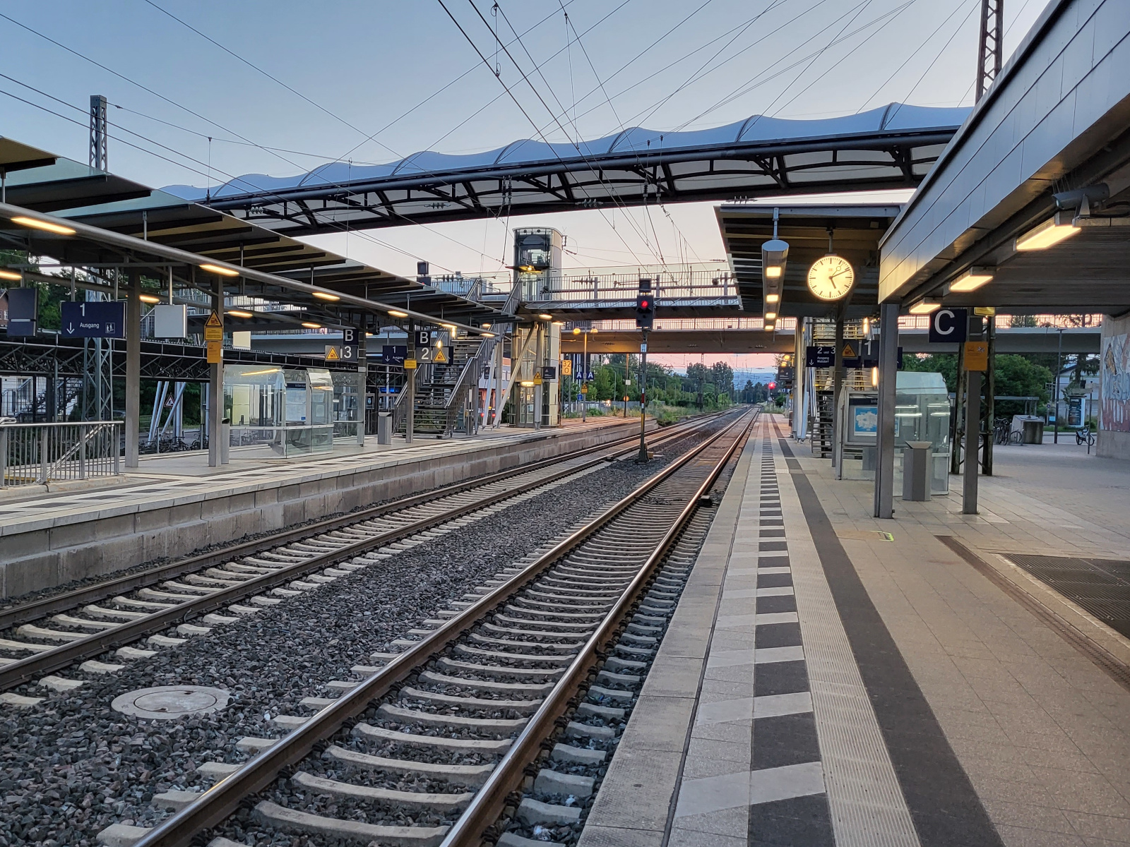 Bahnhof Wiesloch-Walldorf mit Gleisen und überdachtem Steg.