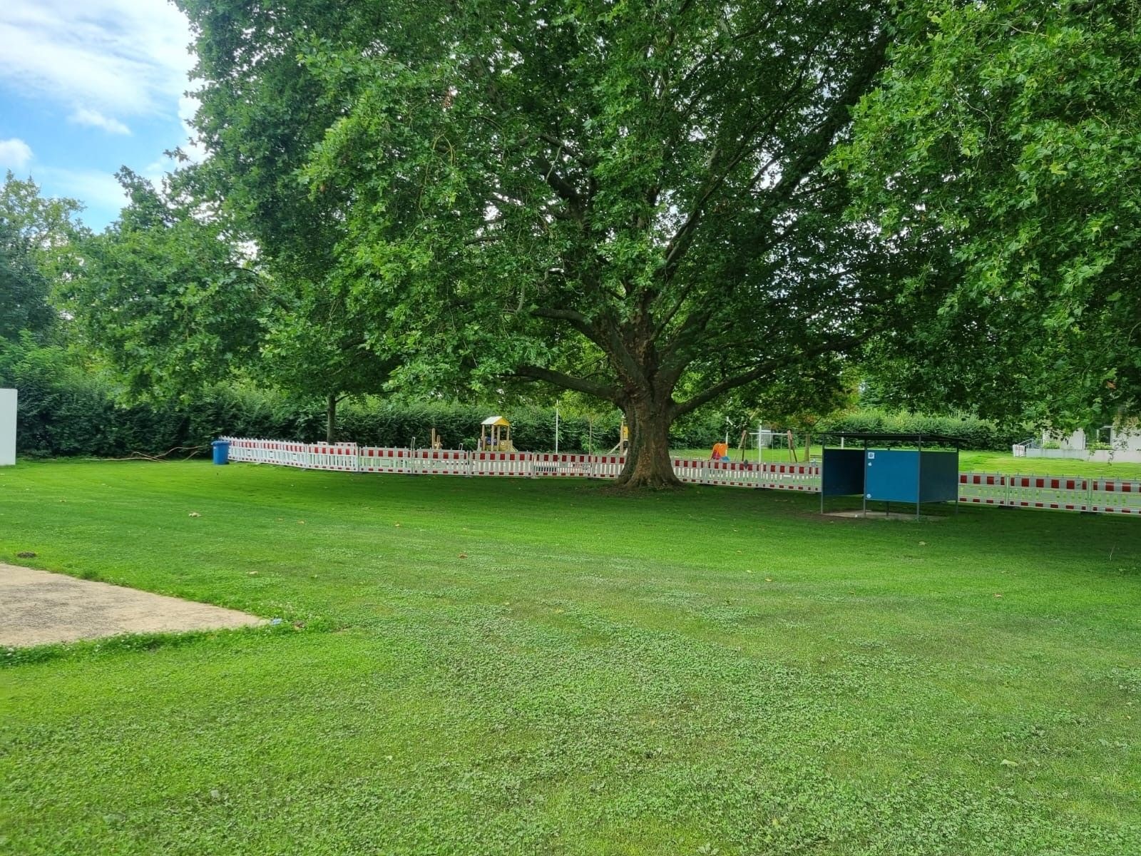 Absperrung der Wiese und des Spielplatzes mit rot-weißen-Zäunen. 