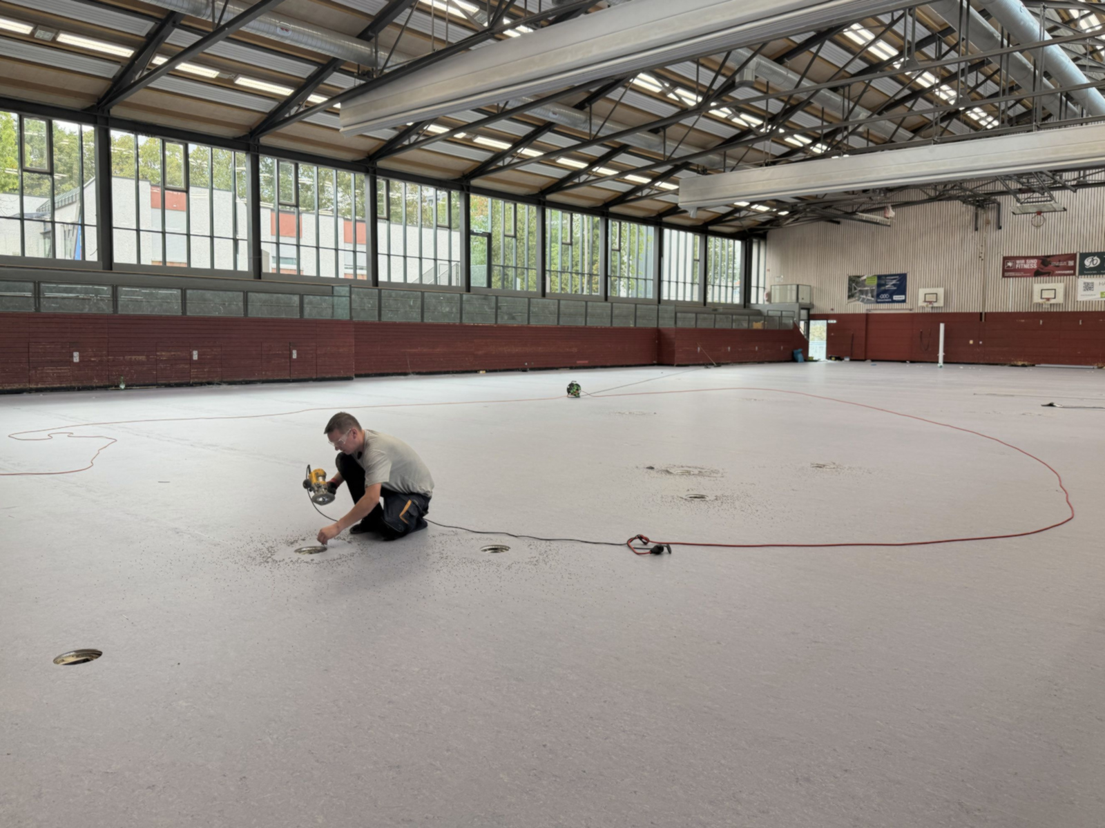 Mann arbeitet an den Bodenhülsen, die beispielsweise für Volleyballnetze genutzt werden. 