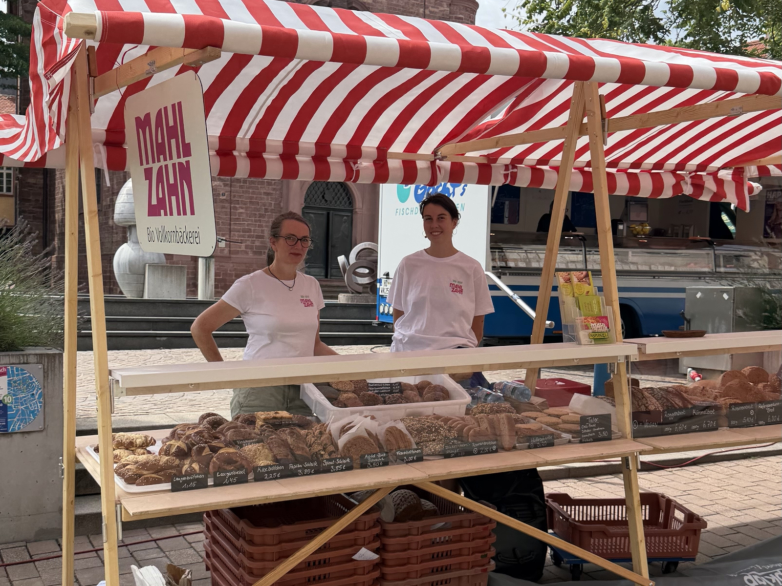Verkaufsstand aus Holz mit rot-weißer Markise. 